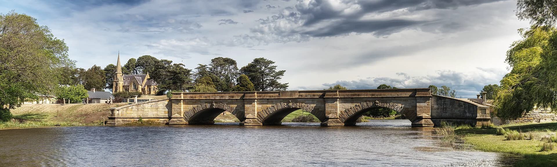The carved sandstone arches of Ross Bridge reflected in the Macquarie River