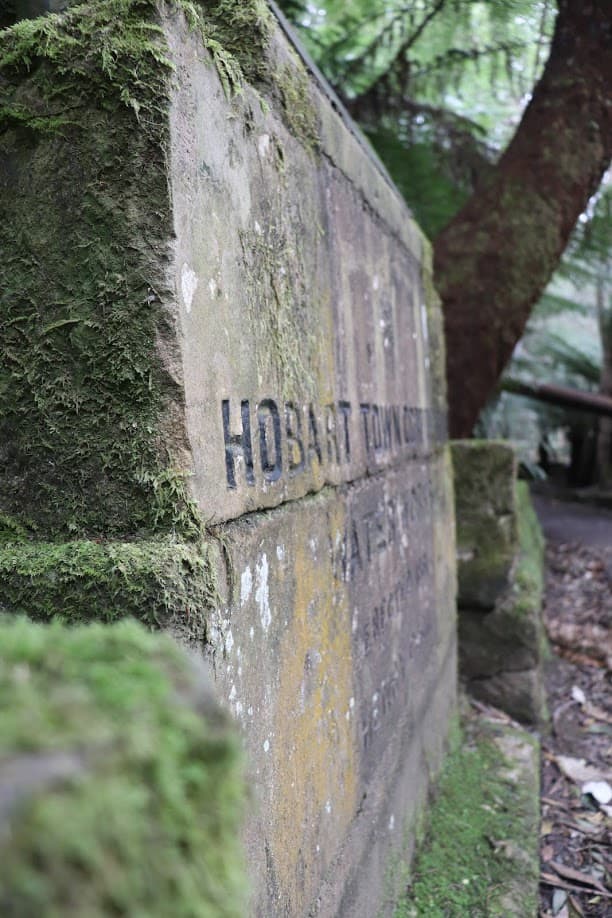 Memorial stones commemorate Mayor Henry Cook and the Hobart Town Corporation Waterworks erected in 1861. In 1960 floods wiped out much of the scenery and surviving tourist facilities at the Fern Tree Bower. Cook’s monument was salvaged and reinstated at the Bower entrance and a plaque unveiled in 1961 commemorates its rehabilitation Plaque reads : Fern Tree Bower These Inscribed Stones Were Salvaged From The Original Water Tower Erected In 1861 And Destroyed By The Great Flood Of 23rd April 1960 This Tablet Is Erected By The Hobart City Council To Commemorate Its Rehabilitation In 1961