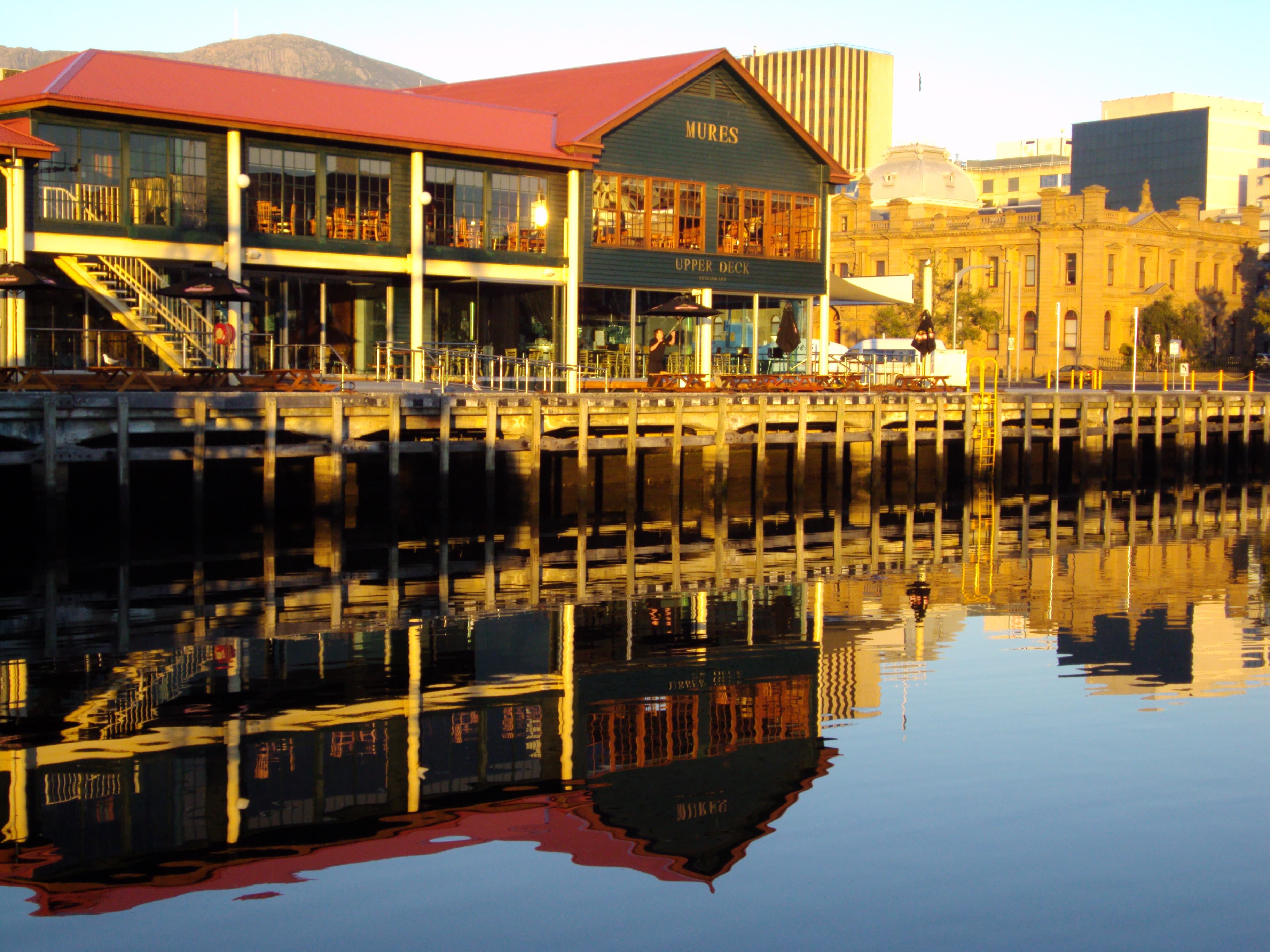 Salamanca Place. In the 1830s as trade opened up in VDL the wharves were on Hunter Island, now Hunter Street. But the waters were more sheltered on the Salamanca side of the harbour so convicts were employed to mine the steep hill side, create a quarry, and built a new shore line so that deep sea facilities for ships could be provided near Salamanca. John Lee Archer was involved in this 1827 plan to re-shape Sullivans Cove which included building up soil in front of the Customs House. In the 1840s the dock facilities moved to Salamanca Place and the large warehouses were built. The apple industry used the sheds right on the wharves in the 20th century. By the 1970s the area was derelict so the Tas. government bought seven warehouses to create an arts centre in 1976. Soon the other warehouses were privately renovated into upmarket galleries, shops and cafes. American Rebel Memorial in Princess Park. In 1839 a number of convicts (around 160) were transported from Canada to Tasmania because they had taken part in a rebellious movement against the British Crown. They were American patriots who had crossed into Canada, but some were French prisoners from French Canada. They had an uprising, were eventually arrested and shipped to Australia but only the American rebels were offloaded in Hobart. (The French rebels were offloaded in Sydney.) They were given hard labour at Port Arthur. The society they belonged to- the Hunters Lodge - had about 20,000 members who urged the Canadians to fight the British. Seven uprisings occurred. Queen Victoria pardoned the Americans between 1844-48. Only a few stayed on in Australia. None stayed in Tasmania. Most returned to the USA. Battery Point, Arthurs Circus, and the Lena House Hotel. Originally guns guarded the harbour from the point, hence the name Battery. Wealthy merchants chose to live there by the 1850s with Alexander McGregor being a good example. He arrived in Hobart from Scotland in 1831.He built up a large whaling fleet and bought Lenna House site from a ship’s captain once he was wealthy. He built this grand house around 1860 with a roof top tower for watching his sailing ships come up the Derwent estuary. It is now a fine hotel, so you can walk in side and look around. Despite two marriages he had no children. Opposite the Lenna is a fine example of a wooden fancy gabled Tudor Gothic style house in Runnymede Street. At the top of Runnymede St is Arthur’s Circus- named after the Governor with its quaint cottages and large horse Chesnuts in the middle of the circus. Is this really Australia? Although in England by the time of its development, Arthur owned this land at Battery Point and sold it off for housing in 1847. The blocks around the circus were all narrow frontage, suitable for workers’ cottages. The cottages were all built around 1850. Battery Point was home to master mariners, shipwrights, seamen, fishermen, shipping agents shipbuilders and as wealthy merchants. St Georges Anglican Church. The story of St George’s begins in 1836 with services commencing in 1838. The church was consecrated by Bishop W. G. Broughton, the first and only Bishop of Australia. St George's was designed in the Neo-Classical style then current in London. The only other examples of this style of church left in Australia are one in Richmond and one in Sydney. The Government architect, John Lee Archer, designed the body of the building; the tower and porch were designed by convict architect, James Blackburn. The church has an unusual layout, with two side aisles instead of a single central aisle. It still has its original cedar box pews. The Government agreed to grant convict labour, stone and timber for the church tower. Lime, lead and glass had to be provided by the church members. By 1847 the tower was finally completed, but the porch and the rooms at the basement of the tower were left unfinished. St George’s porch was not added until 1888. The stone for its fine fluted Grecian columns was quarried at Bellerive. James Blackburn (1803–1854), was a civil engineer, surveyor and architect who had been transported for forgery in 1833. He was pardoned in 1841, but continued in private practice as an architect until 1849. His work included: St Mark's Anglican Church at Pontville (Romanesque), the Lady Franklin Museum (Grecian) and The Grange at Campbell Town (Tudor). Narryna House. Narryna was built as a grand Georgian style house in 1836, one of the first on the hill at Battery Point for Captain Haig. He had built a warehouse down in Salamanca Place in 1833 and lived in that with his family whilst the house was completed. He sold it in 1842 and the property then had many different owners. It is a fine box like, very symmetrical simple Georgian house of grand proportions and constructed with first class quality sandstone. One long time resident was an early mayor of Hobart and a MP. The government bought the house as a TB hospital in 1946. It was established as Australia’s first heritage house museum in 1955. St David’s Park. This was originally the first Hobart graveyard, right opposite the first hospital on the corner of Salamanca Place and Davey Street. Was this a coincidence or expeditious planning? In 1926 the graveyard was converted into this park. In the centre is a fine memorial to Lieutenant Governor Collins. Some of the old headstones are now on the wall behind the Tasmanian Supreme Court. Collins you will remember was the first Lieutenant Governor of VDL and found a new mistress among the Norfolk Islanders, 16 year old Margaret Eddington. In Sydney he had had two children with Ann Yeates in the 1790s. His wife always remained in England. He had two illegitimate children with young Margaret Eddington before he died in 1810. His morals and administration were heavily criticised by the NSW Governor William Bligh.